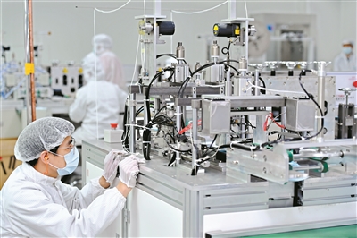 在廣汽集團零部件有限公司車間內，工程師正在調試生產設備。